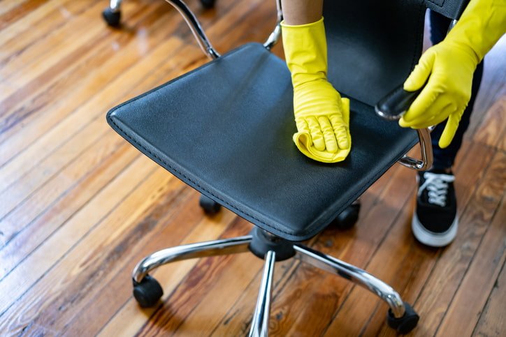 Close-up of hands cleaning an office chair seat and backrest